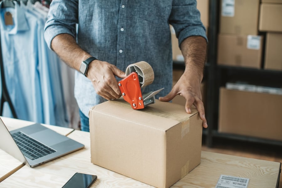 mand pakker varer i kasse