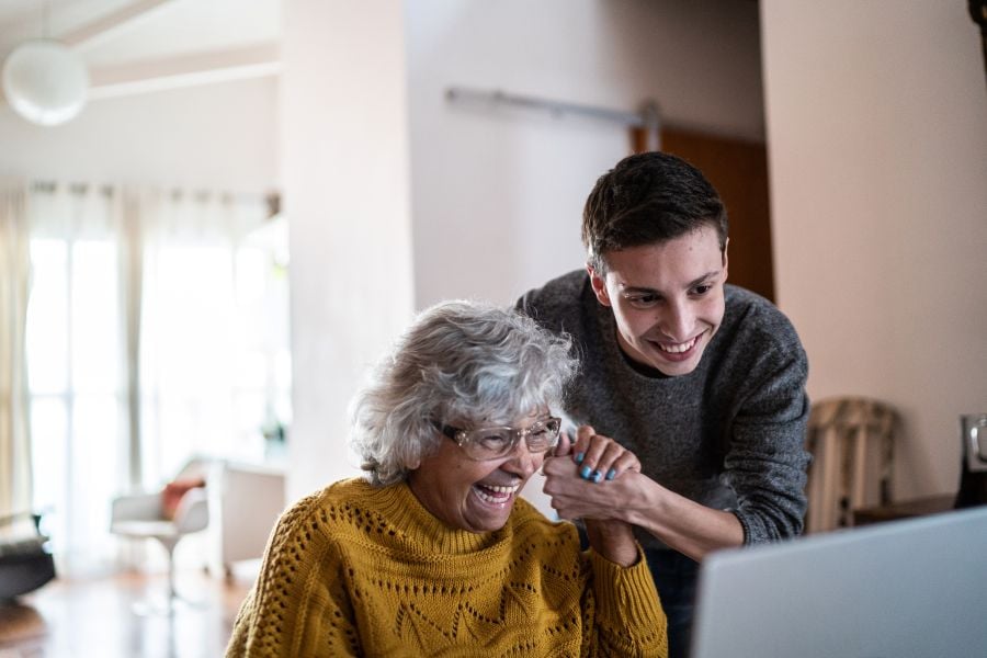 Ung mand hj&aelig;lper &aelig;ldre kvinde med computer