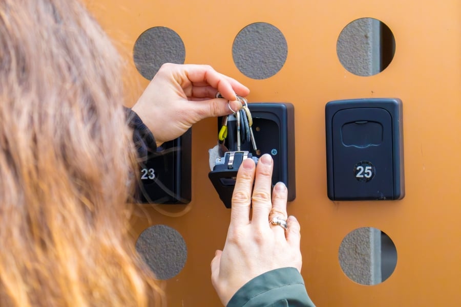 kvinde l&aelig;gger n&oslash;gler i n&oslash;gleboks