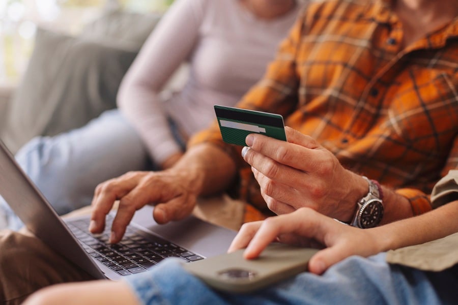 Billede af en, der sidder med sit dankort fremme foran computeren